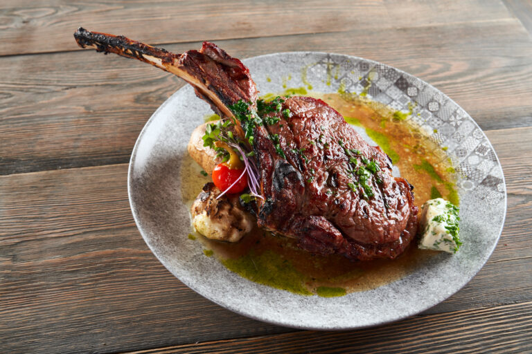 modern roasted lamb on bone with garlic and sauce.