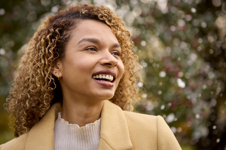 smiling young woman wearing coat standing outside in snowy winter countryside